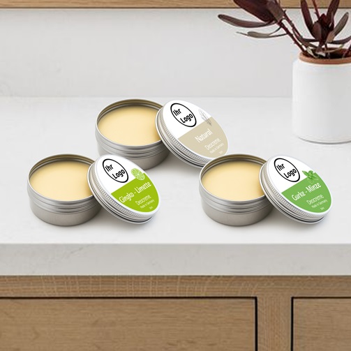 Offene Dosen Deocreme mit eigenem Logo in verschiedenen Duftvarianten auf einer Arbeitsfläche.